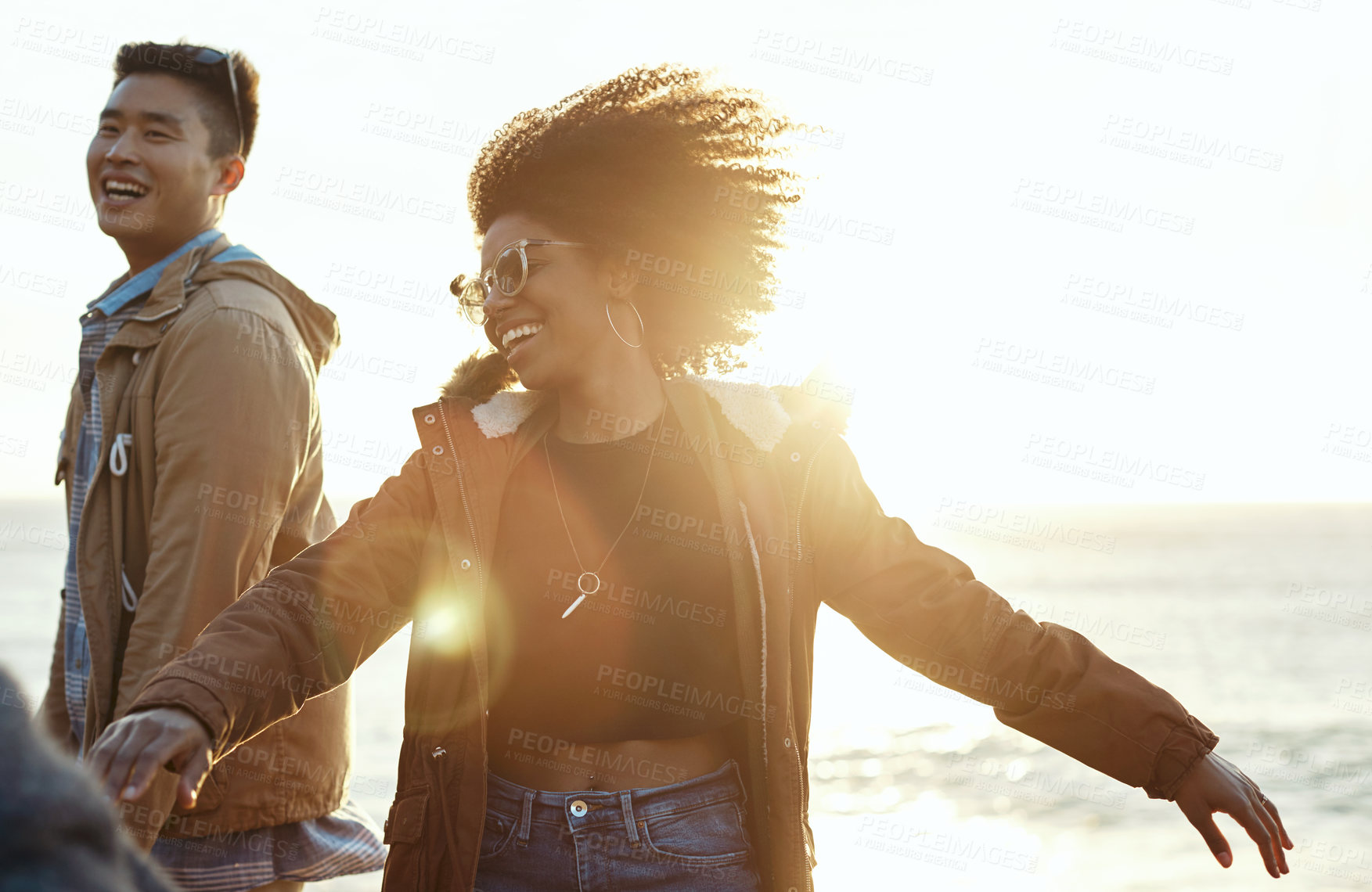 Buy stock photo Shot of happy young friends dancing together along the coast