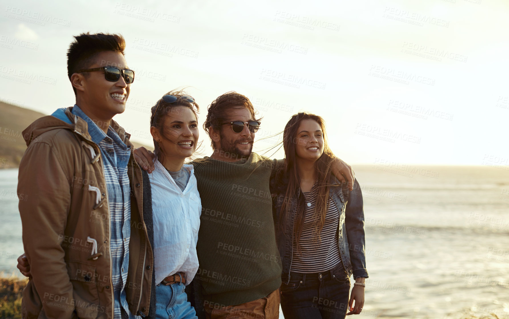 Buy stock photo Shot of a group of happy young friends enjoying a vacation along the coast