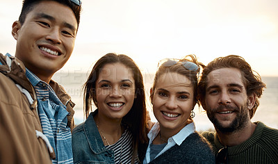 Buy stock photo Shot of a group of happy young friends taking selfies on a vacation along the coast