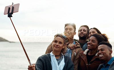 Buy stock photo Shot of a group of happy young friends taking selfies on a vacation along the coast