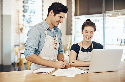 Buy stock photo Shot of two cafe owners having a discussion while using a laptop in their shop