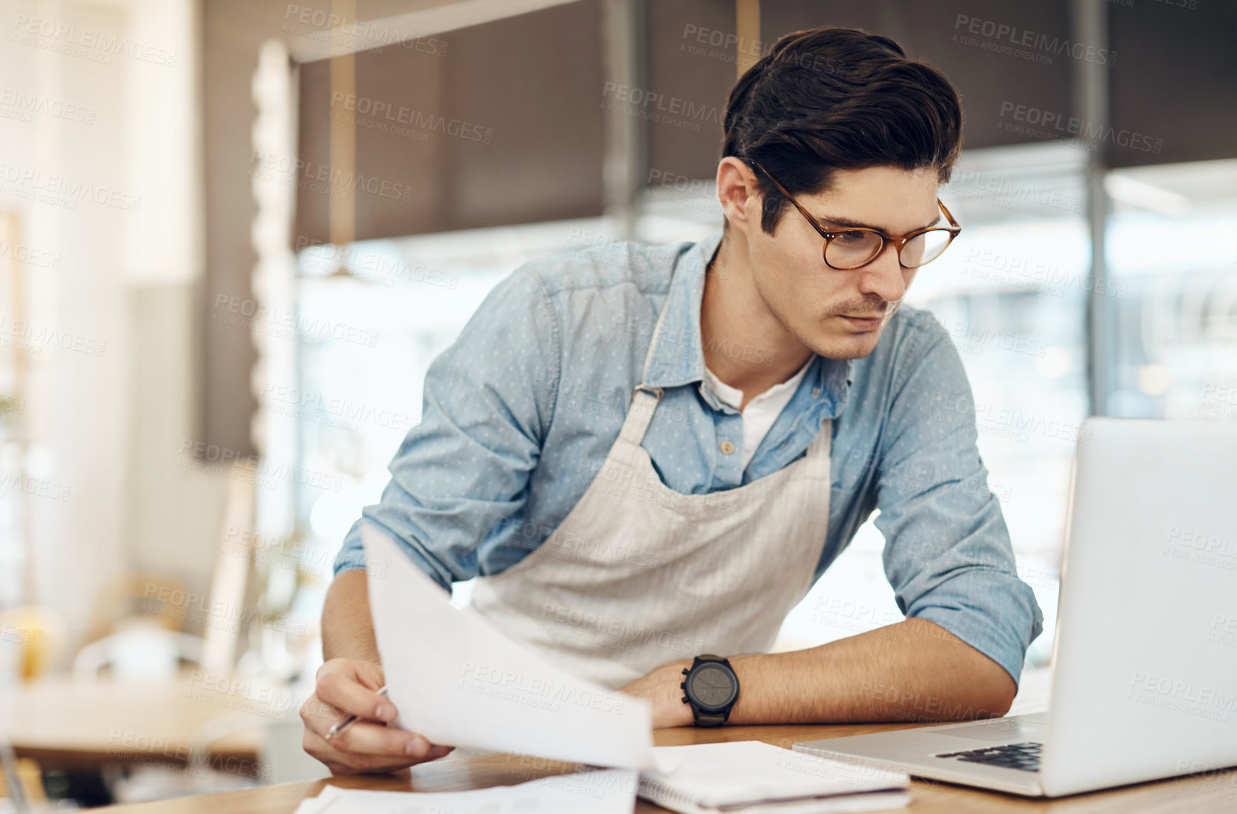 Buy stock photo Owner, man and paperwork in restaurant with laptop, check invoice or online order for small business. Manager, person and reading in diner with computer, planning or document for inventory management