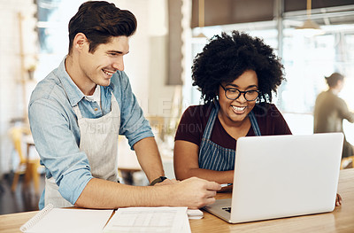 Buy stock photo Shot of two cafe owners having a discussion while using a laptop in their shop