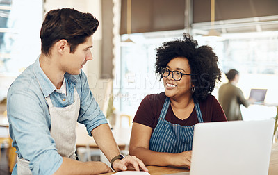 Buy stock photo Shot of two cafe owners having a discussion while using a laptop in their shop