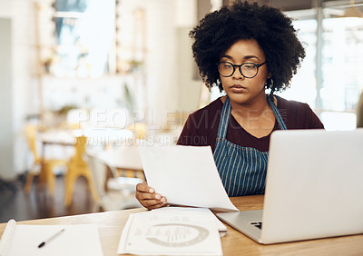 Buy stock photo Shot of a young cafe owner using her laptop and doing paperwork in her shop