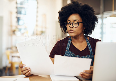 Buy stock photo Shot of a young cafe owner using her laptop and doing paperwork in her shop