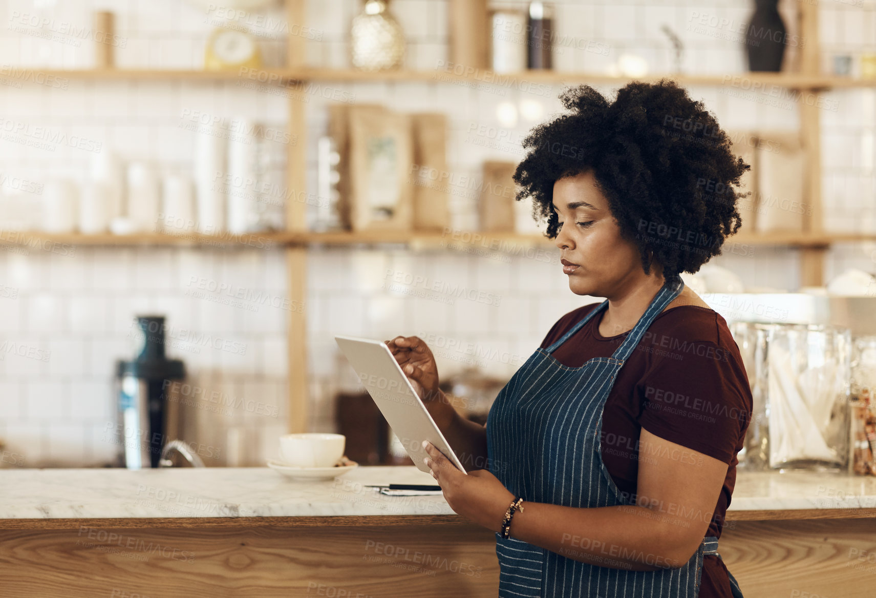 Buy stock photo Shot of a coffee owner using a digital tablet while standing in her cafe