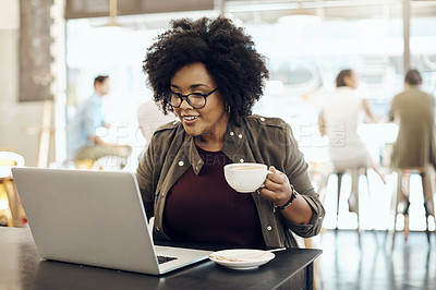 Buy stock photo Cropped shot of a young woman enjoying a cup of coffee while using her laptop in a cafe