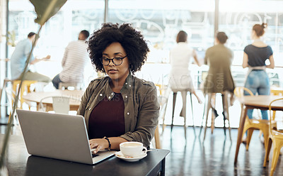 Buy stock photo Cropped shot of a young woman enjoying a cup of coffee while using her laptop in a cafe