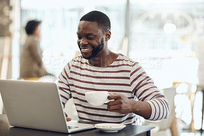Buy stock photo Cropped shot of a young man enjoying a cup of coffee while using his laptop in a cafe
