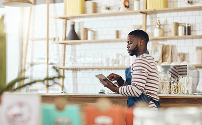 Buy stock photo Cropped shot of a young shop owner using a digital tablet in his cafe