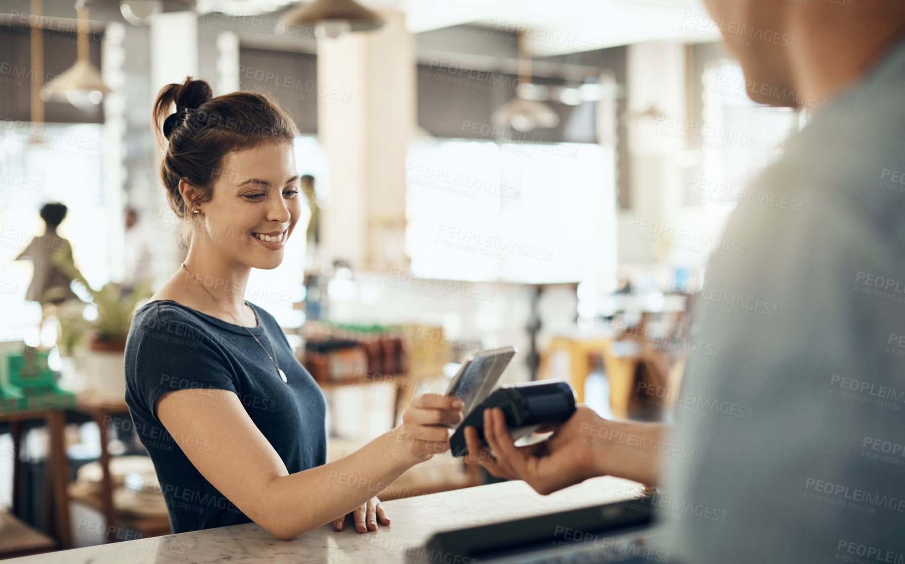 Buy stock photo Shot of a young woman making a payment using her cellphone in a cafe