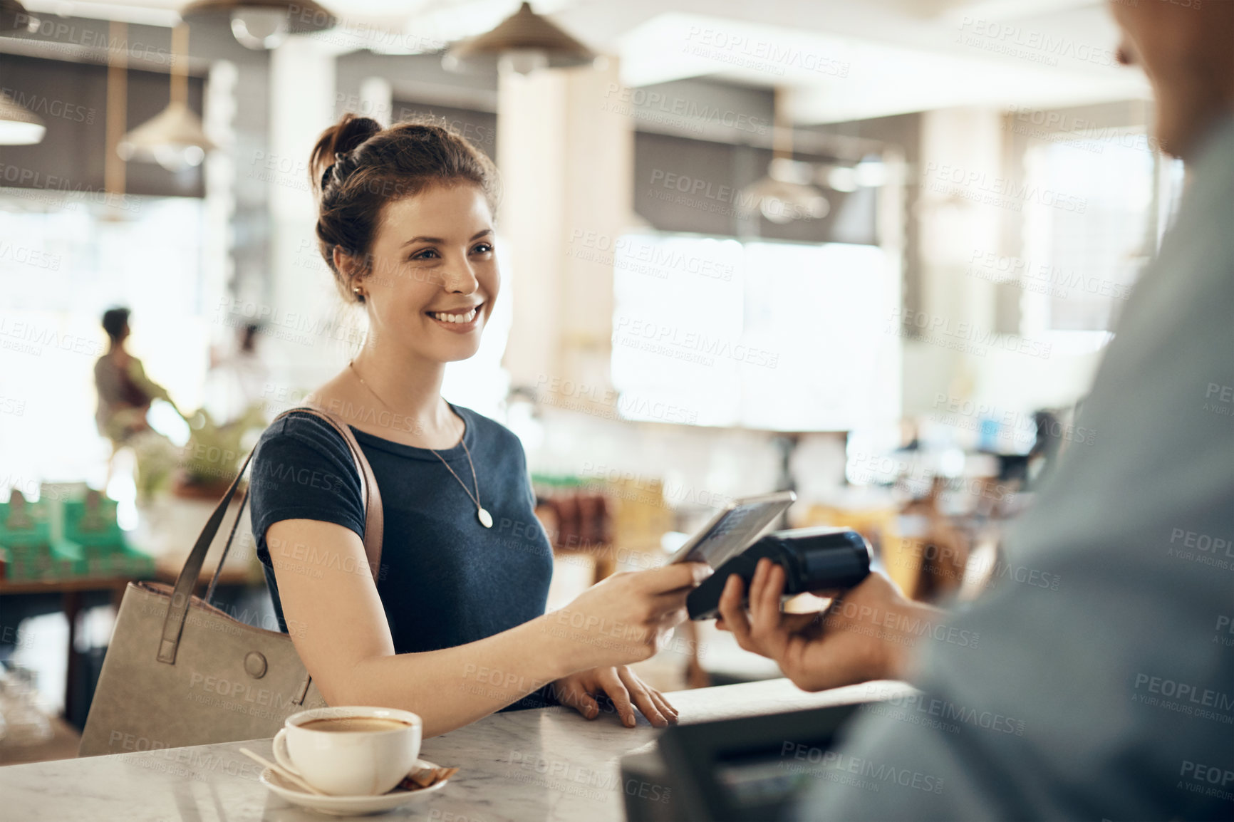 Buy stock photo Shot of a young woman making a payment using her cellphone in a cafe