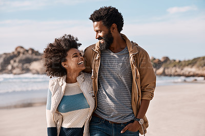 Buy stock photo Shot of a happy young couple going for a romantic walk along the beach