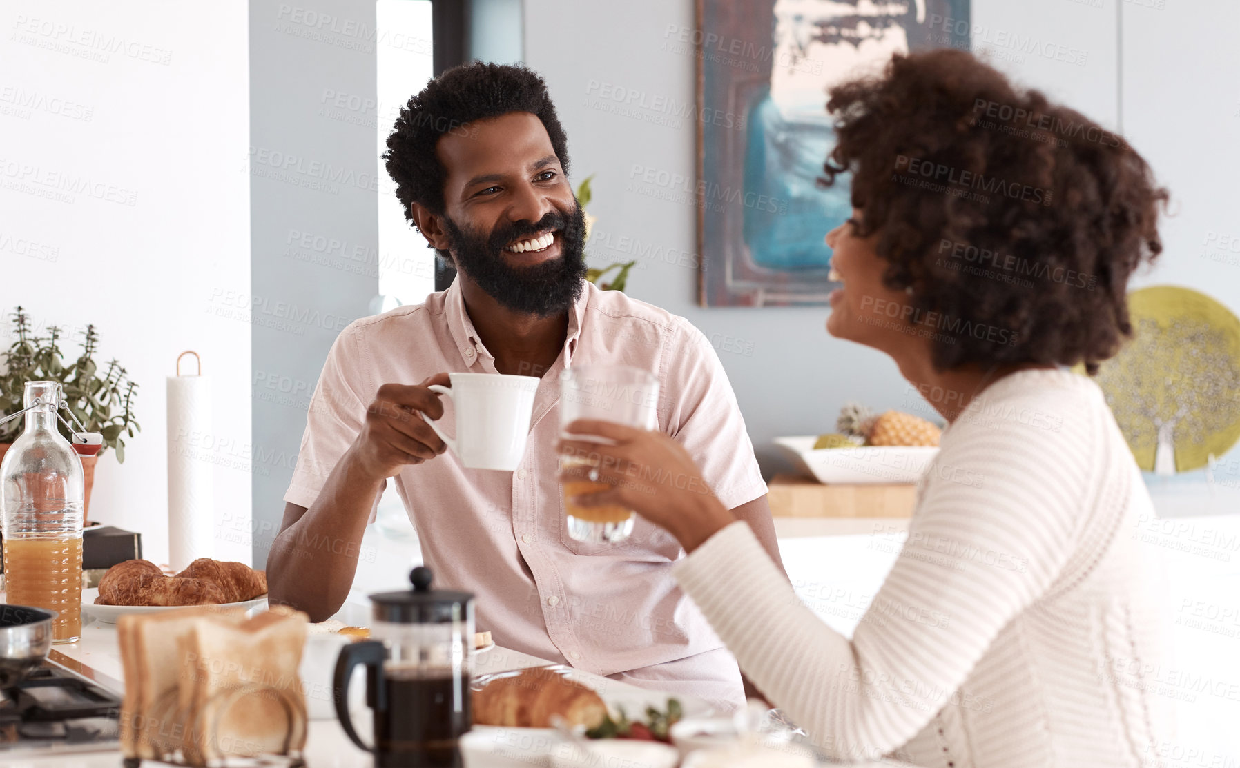 Buy stock photo Couple, laugh and breakfast at kitchen counter with drinks, funny story and nutrition for wellness. Married, African people and happy in home with beverage, healthy food and morning meal with humor.