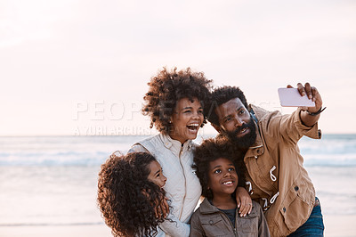 Buy stock photo Shot of a happy young family taking a selfie with a smartphone at the beach