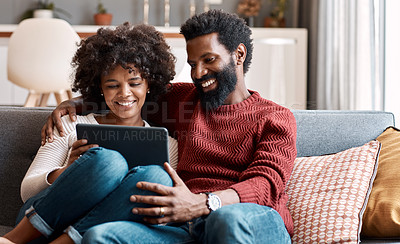 Buy stock photo Shot of an affectionate couple using a digital tablet while relaxing on the sofa at home