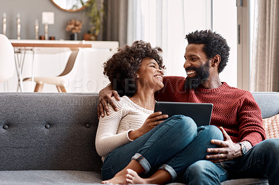 Buy stock photo Shot of an affectionate couple using a digital tablet while relaxing on the sofa at home