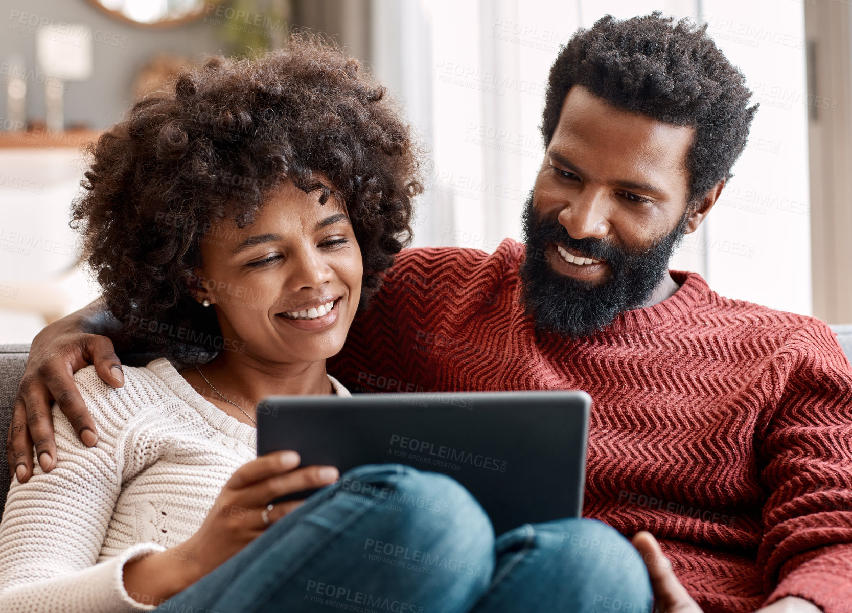 Buy stock photo Shot of an affectionate couple using a digital tablet while relaxing on the sofa at home