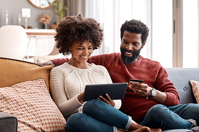 Buy stock photo Shot of a man holding a credit card while browsing on a digital tablet with his wife