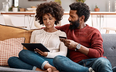 Buy stock photo Shot of a man holding a credit card while browsing on a digital tablet with his wife