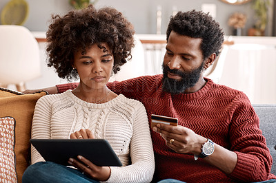 Buy stock photo Shot of a man holding a credit card while browsing on a digital tablet with his wife