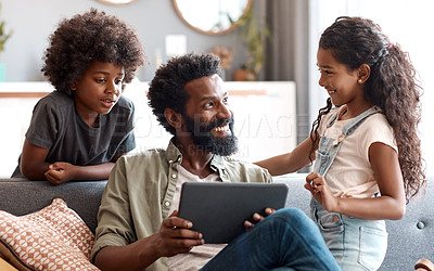 Buy stock photo Shot of two adorable young siblings using a digital tablet while bonding and relaxing with their father at home
