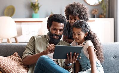 Buy stock photo Shot of two adorable young siblings using a digital tablet while bonding and relaxing with their father at home
