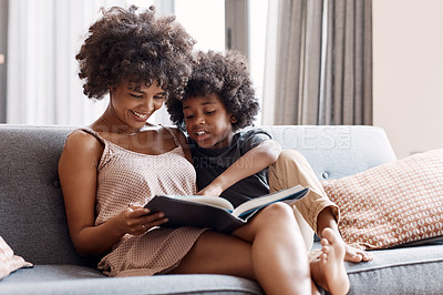 Buy stock photo Shot of an adorable little boy reading a a book and spending time with his mother at home