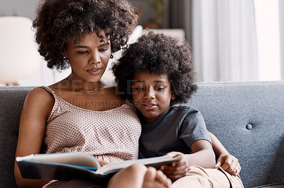 Buy stock photo Shot of an adorable little boy reading a book and spending time with his mother at home