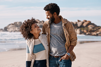 Buy stock photo Shot of a happy young couple going for a romantic walk along the beach