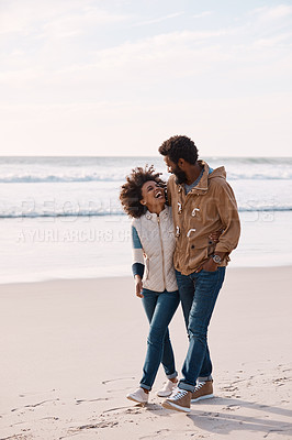 Buy stock photo Shot of a happy young couple going for a romantic walk along the beach