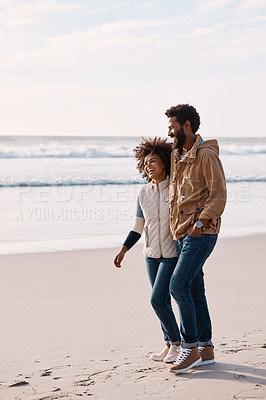 Buy stock photo Shot of a happy young couple going for a romantic walk along the beach