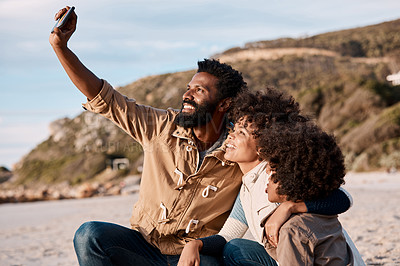 Buy stock photo Shot of a happy young family taking a selfie with a smartphone at the beach