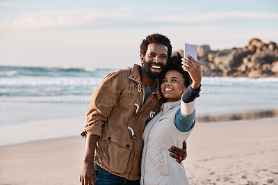 Buy stock photo Shot of a happy young couple taking selfies with a smartphone at the beach