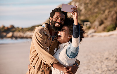 Buy stock photo Shot of a happy young couple taking selfies with a smartphone at the beach