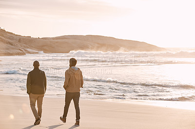Buy stock photo Rearview shot of a young man going for a walk along the beach with his father