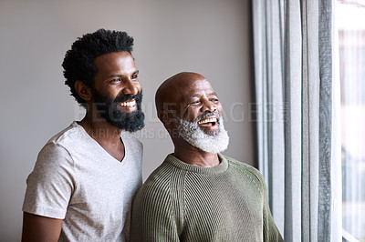 Buy stock photo Shot of a happy young man and his father looking out the window together at home