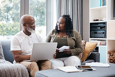 Buy stock photo Shot of a mature couple using a laptop while going through paperwork together at home