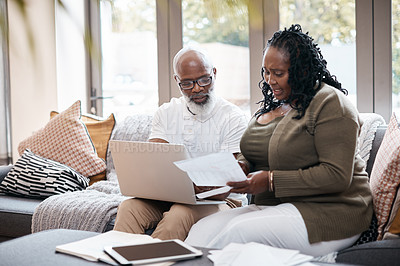 Buy stock photo Shot of a mature couple using a laptop while going through paperwork together at home