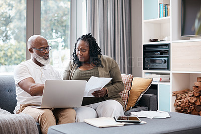 Buy stock photo Shot of a mature couple looking stressed out while going through paperwork together at home