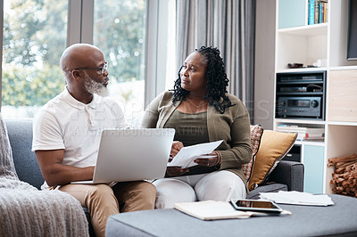 Buy stock photo Shot of a mature couple looking stressed out while going through paperwork together at home