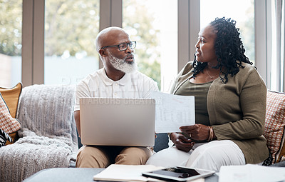 Buy stock photo Shot of a mature couple using a laptop while going through paperwork together at home