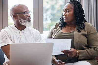 Buy stock photo Shot of a mature couple looking stressed out while going through paperwork together at home