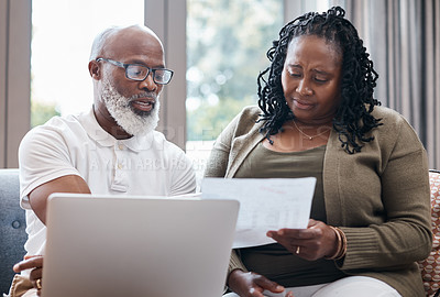 Buy stock photo Shot of a mature couple looking stressed out while going through paperwork together at home