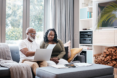 Buy stock photo Shot of a mature couple using a laptop while going through paperwork together at home