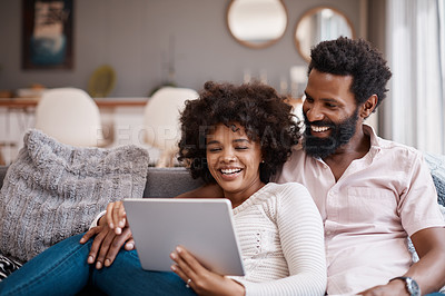 Buy stock photo Shot of an affectionate couple using a digital tablet while relaxing on the sofa at home