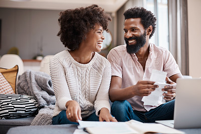 Buy stock photo Shot of a couple looking at paperwork while using a laptop in their living room