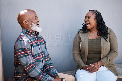 Buy stock photo Shot of a mature couple laughing while sitting against a grey background