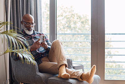 Buy stock photo Shot of a mature man using a cellphone while relaxing on a sofa at home